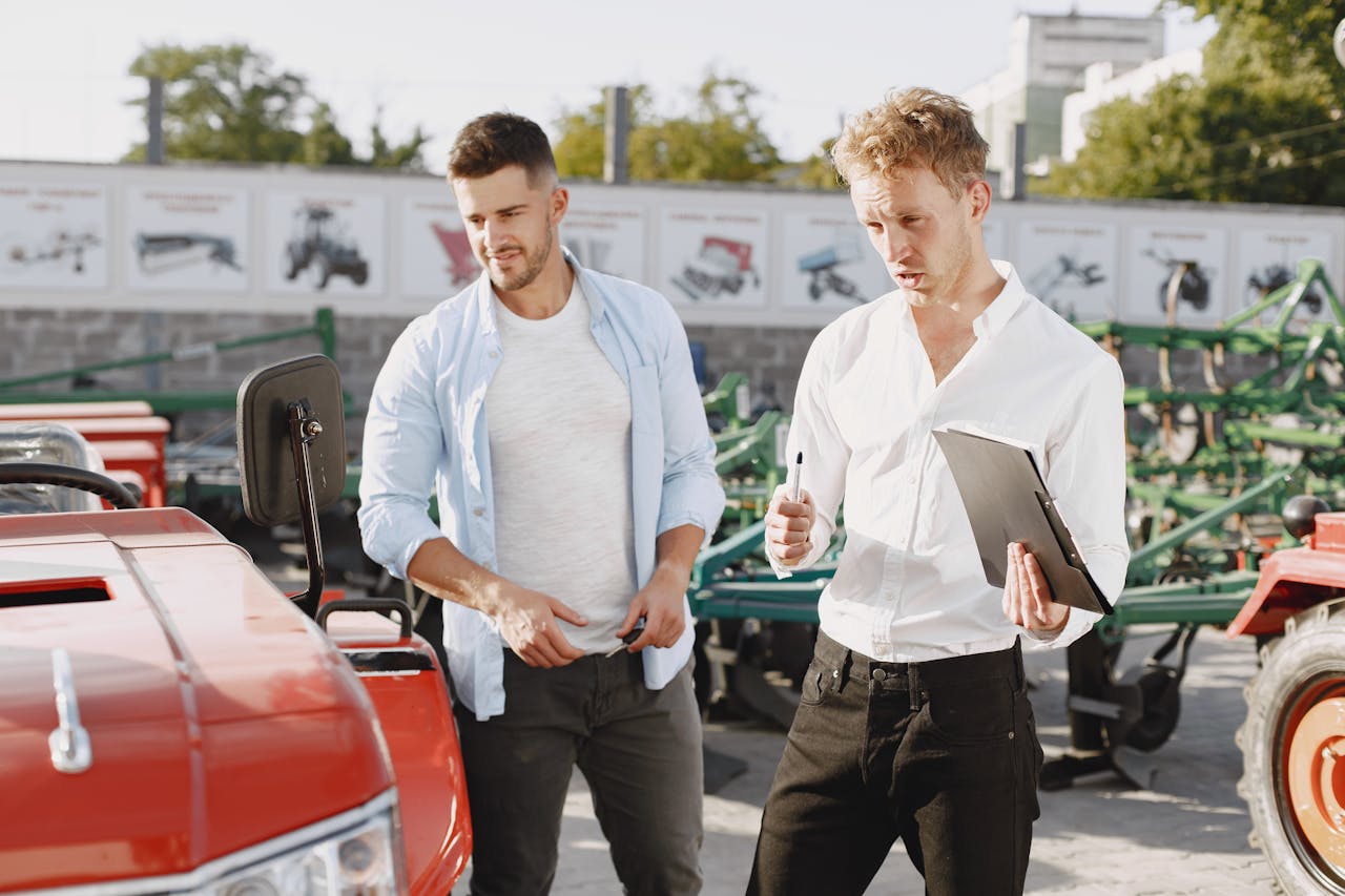 our-experience Two men engaging in a discussion about a tractor sale at an outdoor dealership.